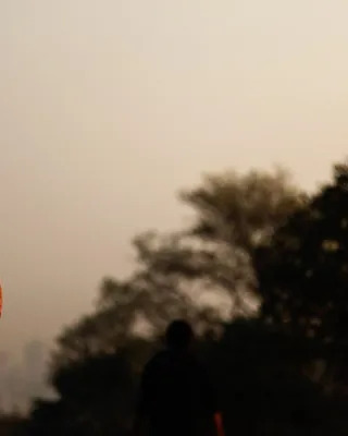 A person facing the sunrise with hands pressed together in quiet reflection