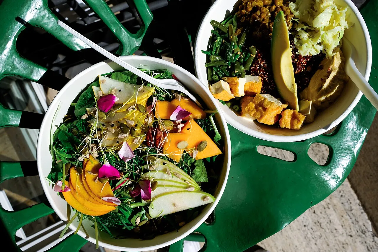 An overhead view of a colorful grain bowl with roasted vegetables and greens