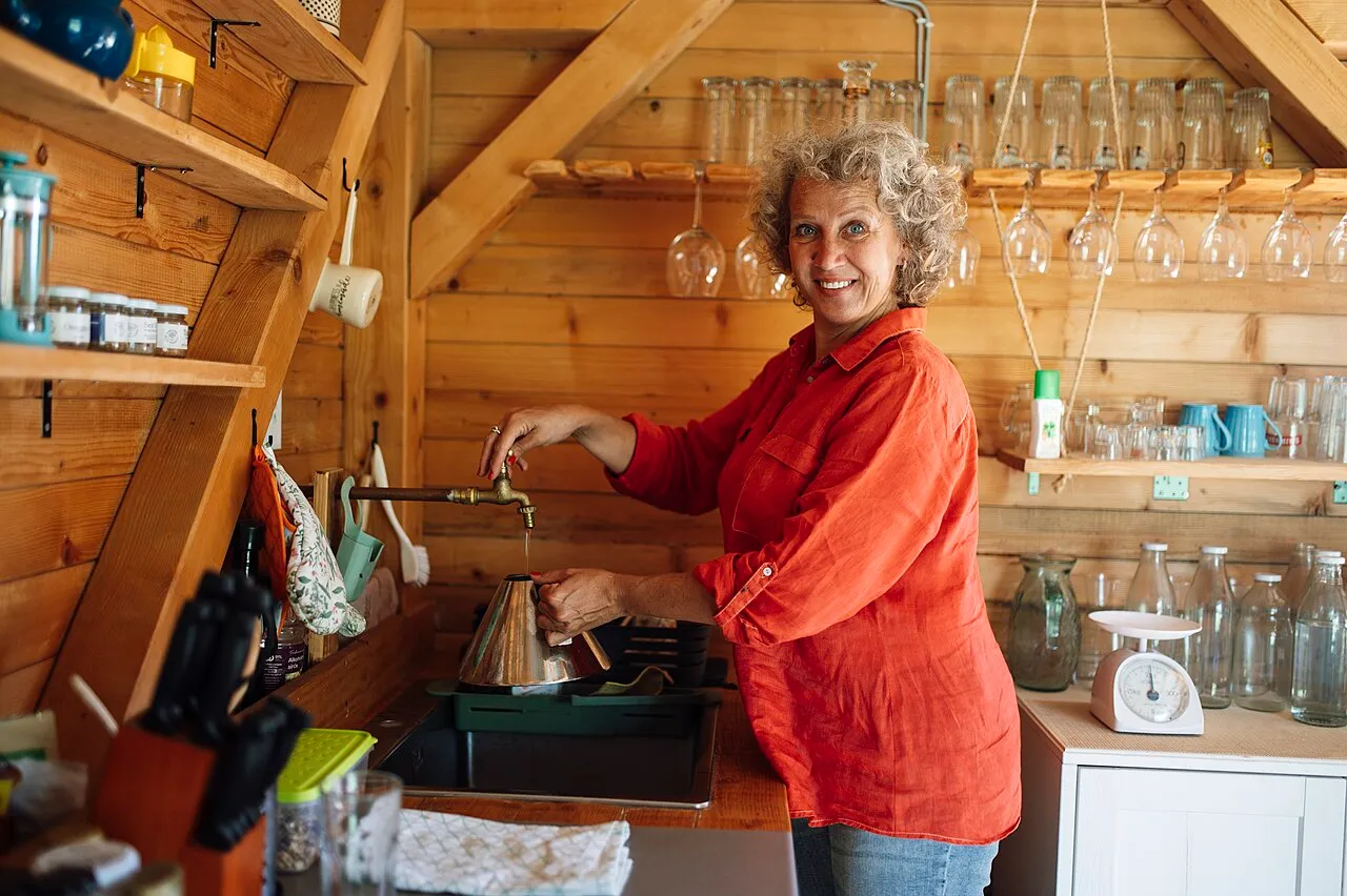 A woman smiling while preparing coffee in a cozy wooden kitchen