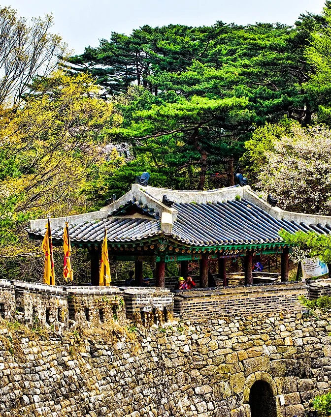 Stone steps and a walled garden path leading up a wooded hillside temple site