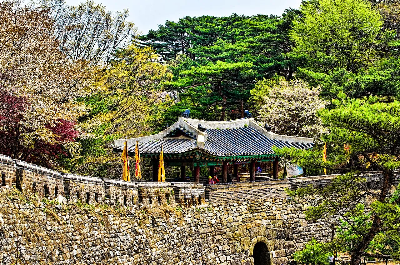 Stone steps and a walled garden path leading up a wooded hillside temple site